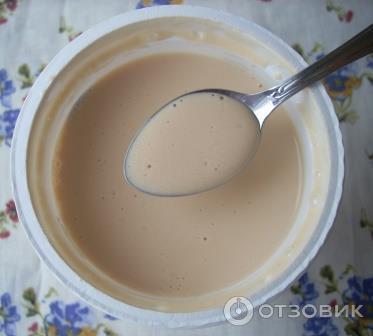 открытый стакан с ряженкой и в нем ложечка